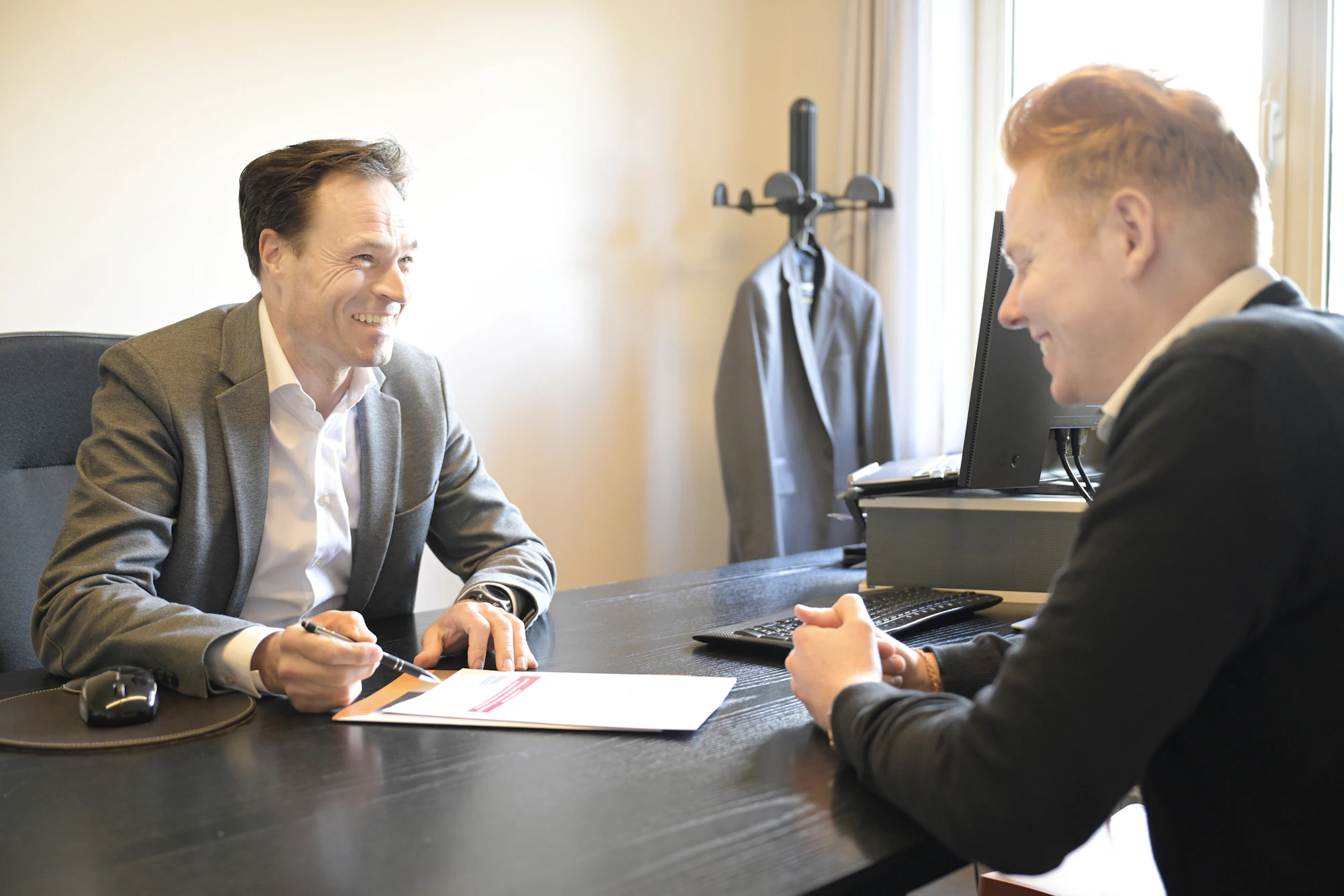 Two business owners talking across a desk with documents